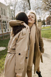 Smiling woman with arm around embracing daughter - VIVF00174