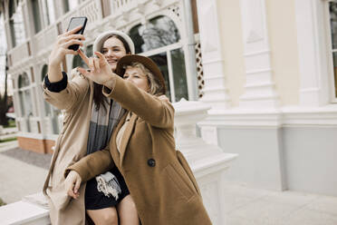 Mother and daughter taking selfie through smart phone near building - VIVF00175