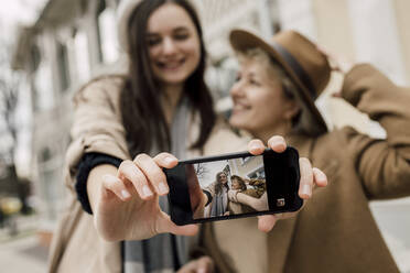 Tochter zeigt ihr Selfie mit der Mutter auf dem Smartphone-Bildschirm - VIVF00178