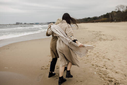 Mother and daughter strolling on sand at beach - VIVF00185