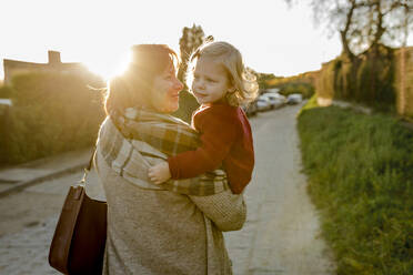 Grandmother carrying granddaughter on footpath at sunset - VIVF00196