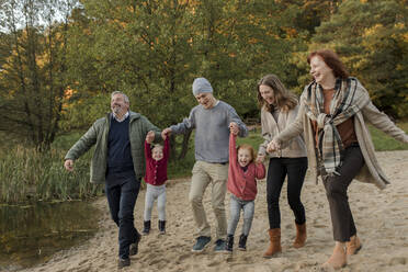 Verspielte Familie, die ihre Freizeit miteinander verbringt und im Sand spazieren geht - VIVF00211