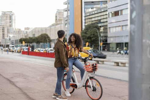 Junger Mann mit Freundin auf dem Fahrrad sitzend am Fußweg - JCCMF07951