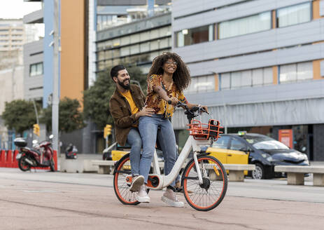 Glücklicher Freund genießt mit Freundin Fahrrad fahren auf dem Gehweg - JCCMF07953