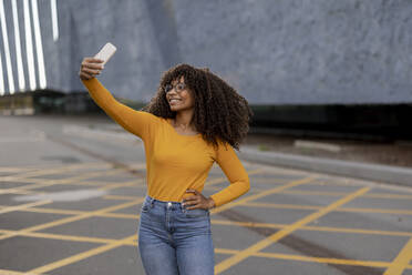 Glückliche junge Frau, die ein Selfie über ihr Smartphone macht - JCCMF07971