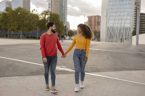 Junges Paar hält sich an den Händen und geht auf einem Fußweg - JCCMF07974