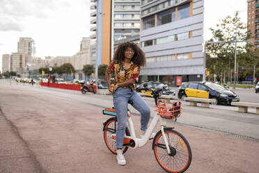 Lächelnde junge Frau auf dem Fahrrad sitzend am Fußweg - JCCMF08038