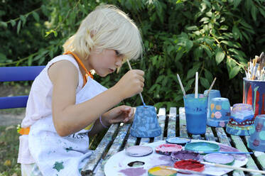 Kleines Mädchen malt Blumentöpfe im Garten - GISF00946