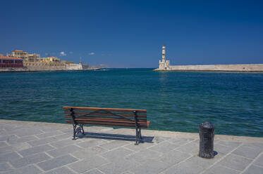 Griechenland, Kreta, Chania, Leere Hafenbank mit Leuchtturm im Hintergrund - MHF00671