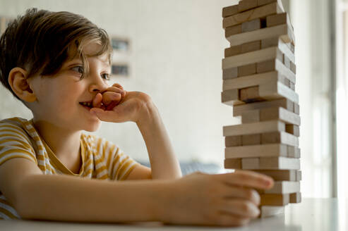 Konzentrierter Junge spielt zu Hause ein Spiel zum Entfernen von Blöcken - ANAF00524
