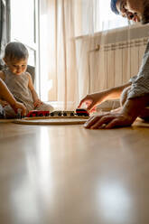 Father spending leisure time with sons playing toy at home - ANAF00528