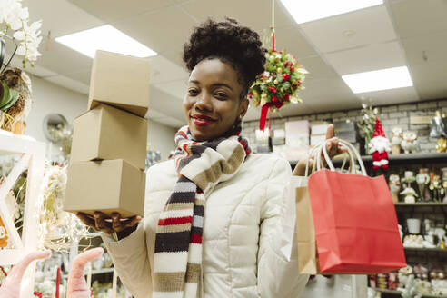 Lächelnde Frau mit Geschenken und Einkaufstüten in einem Geschäft - OSF01140