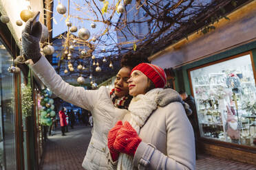 Freunde in warmer Kleidung machen ein Selfie mit ihrem Smartphone auf der Straße - OSF01142