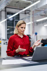 Businesswoman doing video call on laptop at factory - DIGF19356