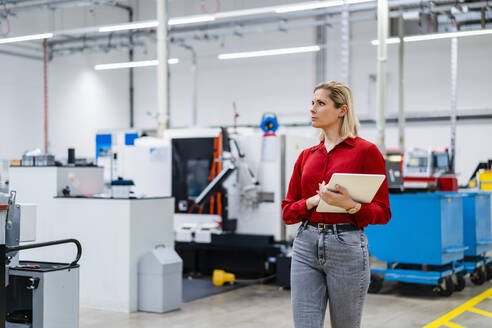 Businesswoman walking with tablet PC in factory - DIGF19366