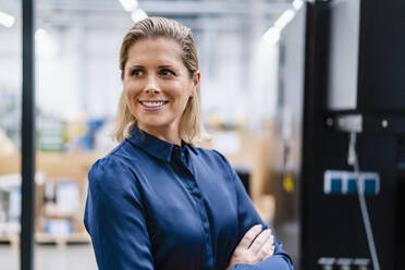 Smiling businesswoman wearing blue shirt at factory - DIGF19371