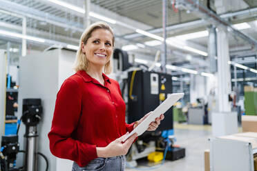 Happy businesswoman with tablet PC in industry - DIGF19386