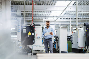 Businessman using tablet PC standing in industry - DIGF19390