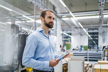 Smiling businessman with tablet PC at factory - DIGF19393