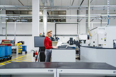 Businesswoman working on laptop in industry - DIGF19419