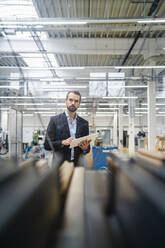 Thoughtful businessman with tablet PC in factory - DIGF19448