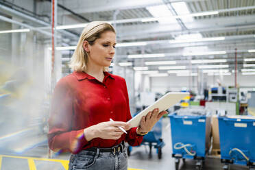 Businesswoman with tablet PC standing in industry - DIGF19452