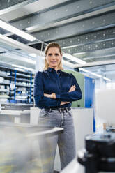 Confident businesswoman with arms crossed standing in factory - DIGF19497