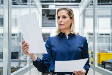 Focused businesswoman analyzing documents at factory - DIGF19502