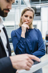 Young businessman discussing with colleague over document in factory - DIGF19513