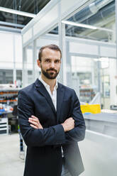 Businessman wearing blazer standing with arms crossed in industry - DIGF19519