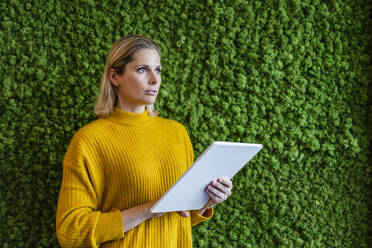 Contemplative businesswoman with tablet PC by wall - DIGF19534