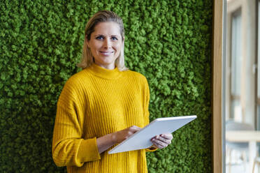 Smiling businesswoman with tablet PC in office - DIGF19536