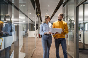 Businesswoman discussing over tablet computer with colleague at workplace - DIGF19582