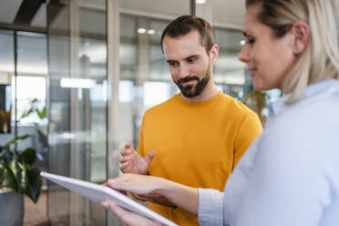 Businessman talking to businesswoman using tablet PC at office - DIGF19607