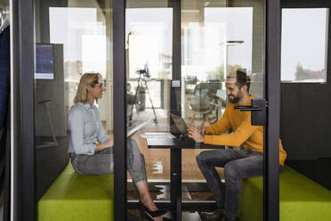 Business colleagues discussing with each other sitting in office cabin - DIGF19626