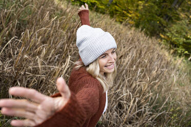 Smiling mature woman dancing with arms outstretched in meadow - HMEF01444