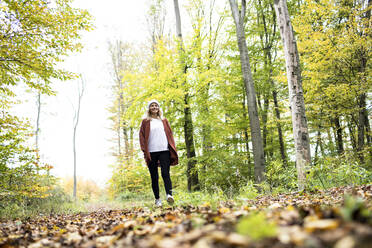 Reife Frau erkundet Wald am Wochenende im Herbst - HMEF01450