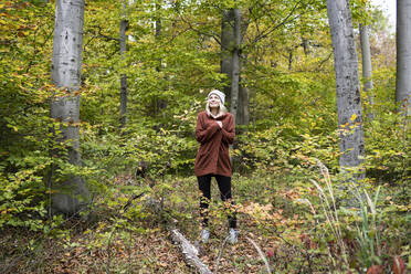 Mature woman standing amidst trees in forest on weekend - HMEF01451