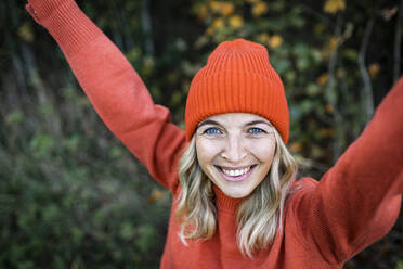 Lächelnde reife Frau mit orangefarbener Strickmütze am Wochenende - HMEF01463