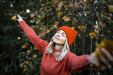 Mature woman with eyes closed in autumn forest on weekend - HMEF01466