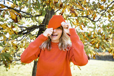 Mature woman looking through knit hat in forest - HMEF01471