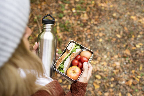 Woman holding food box and stainless steel bottle on weekend - HMEF01479