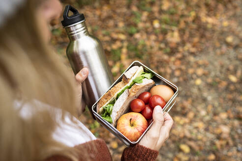 Woman's hand holding food box and water bottle - HMEF01480