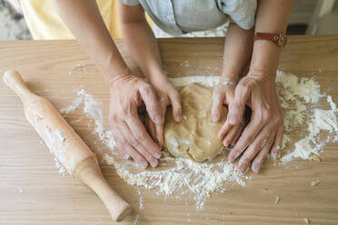 Hands of woman kneading cookie dough on table at home - SVKF00761