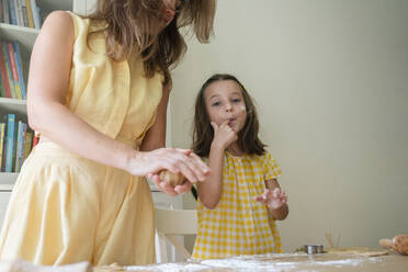 Niedliches Mädchen bereitet mit ihrer Mutter zu Hause Kekse zu - SVKF00770