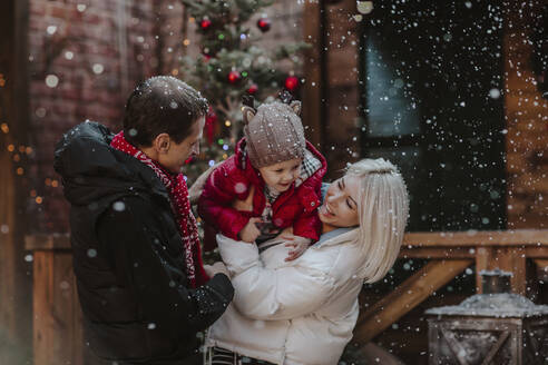 Fröhlicher Vater und Mutter spielen mit Sohn im Schnee - MDOF00226