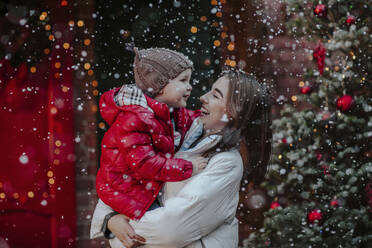 Fröhliche Frau mit Sohn genießt im Schnee - MDOF00227