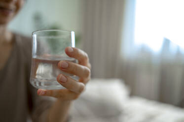 Woman holding glass of water at home - ANAF00541