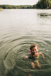 Porträt eines Jungen, der in den Ferien auf einem See schwimmt - MASF32624