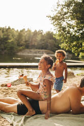 Smiling girl with ice cream sitting on father back during vacation - MASF32638